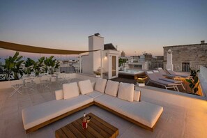 Une terrasse sur le toit avec un canapé blanc, des fauteuils et une table en bois.