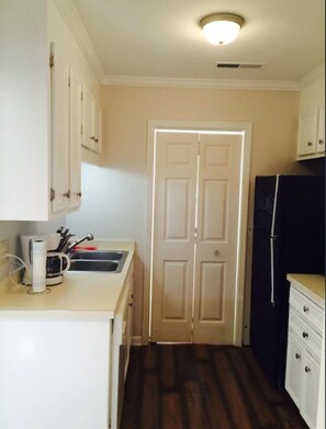 A small kitchen with a sink, cabinets, and a refrigerator.