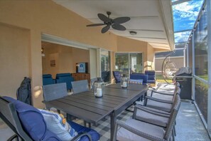 A covered patio area with a table and chairs, a ceiling fan, and a view of the outdoors.