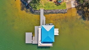Luchtbeeld van een steiger die zich uitstrekt in het water, met een gebouw dat een blauw dak en een witte gevel heeft.