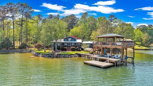 A lakeside property with a house, dock, and wooden gazebo.