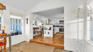 A spacious kitchen with white cabinets, a wooden dining table, and a staircase leading to an upper level.