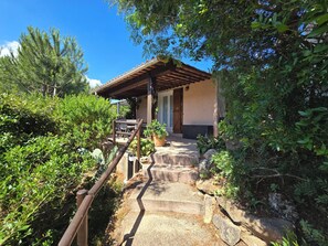 Una escalera de piedra que conduce a un edificio con techo de madera, rodeado de abundante vegetación.