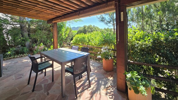 Une terrasse extérieure avec une table et des chaises, entourée de verdure et offrant une vue sur le paysage.