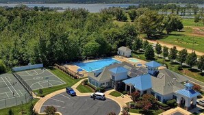 Zona residencial con una piscina grande, una cancha de baloncesto y una casa con techo azul.