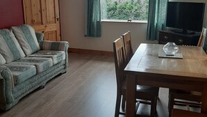 Un salon comprenant une table à manger en bois, un canapé et un téléviseur.
