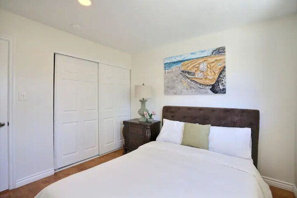 A bedroom with a large bed, a nightstand, a lamp, and a painting on the wall. - Disneyland,Golf course,Bike Trail to beach,5 rooms (Santa Ana)