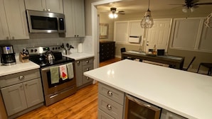 Una cocina moderna con gabinetes grises, electrodomésticos de acero inoxidable y piso de madera.