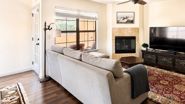 A living room with a sofa, a television, a fireplace, and a patterned rug. - 2-Bedroom Condo in the Foothills, La Encantada, Galleries and Restaurants! (Tucson)