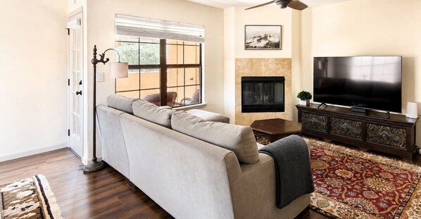 A living room with a sofa, a television, a fireplace, and a patterned rug.