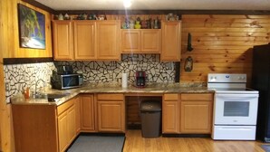 Una cocina con armarios de madera, microondas, cafetera y estufa.