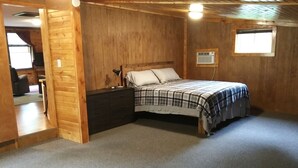 Un dormitorio con cama, cómoda, ventana y unidad de aire acondicionado.