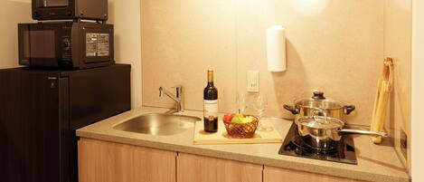 A kitchen with a refrigerator, microwave, sink, and a stove.