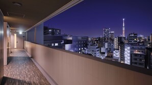 A corridor with a city view, featuring modern buildings and a prominent tower. - MONday Apart Premium Ueno (Tokyo)