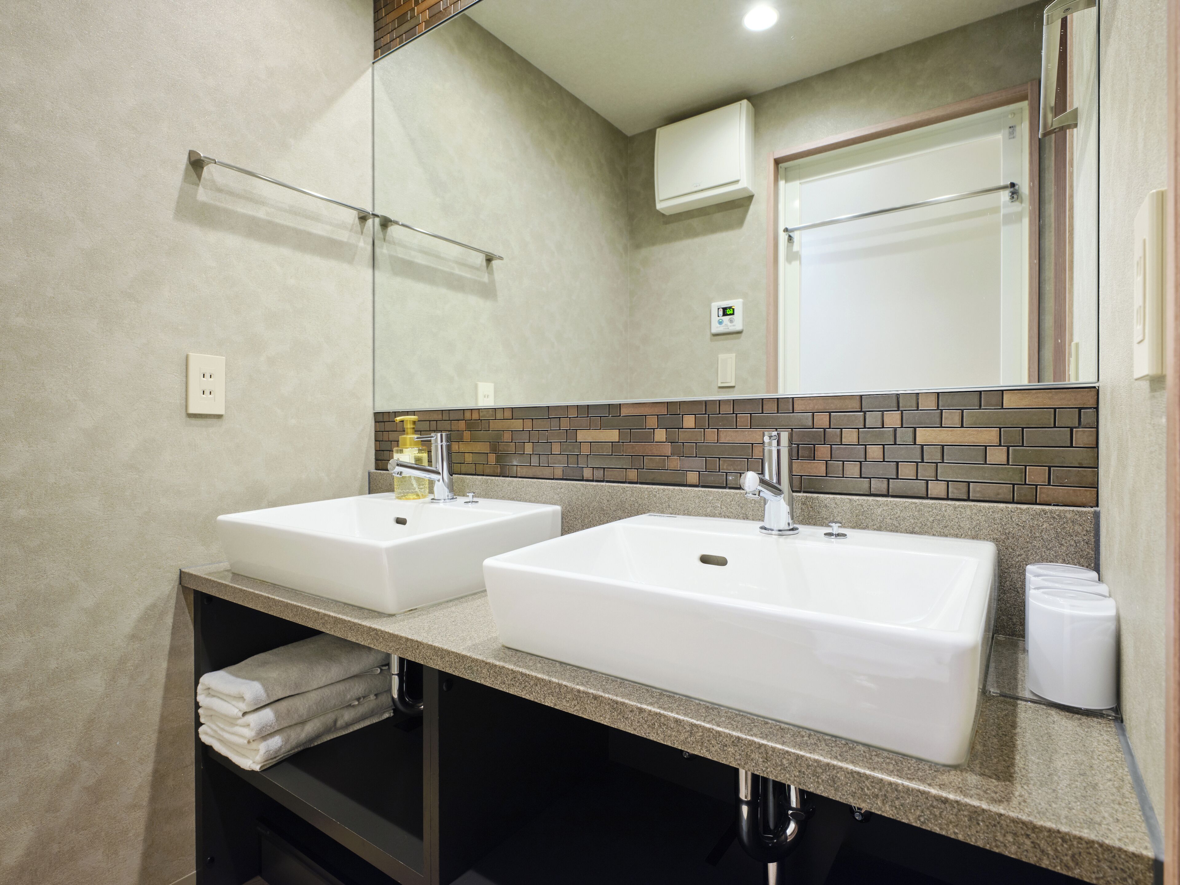 A bathroom with two sinks, a mirror, and a towel rack.