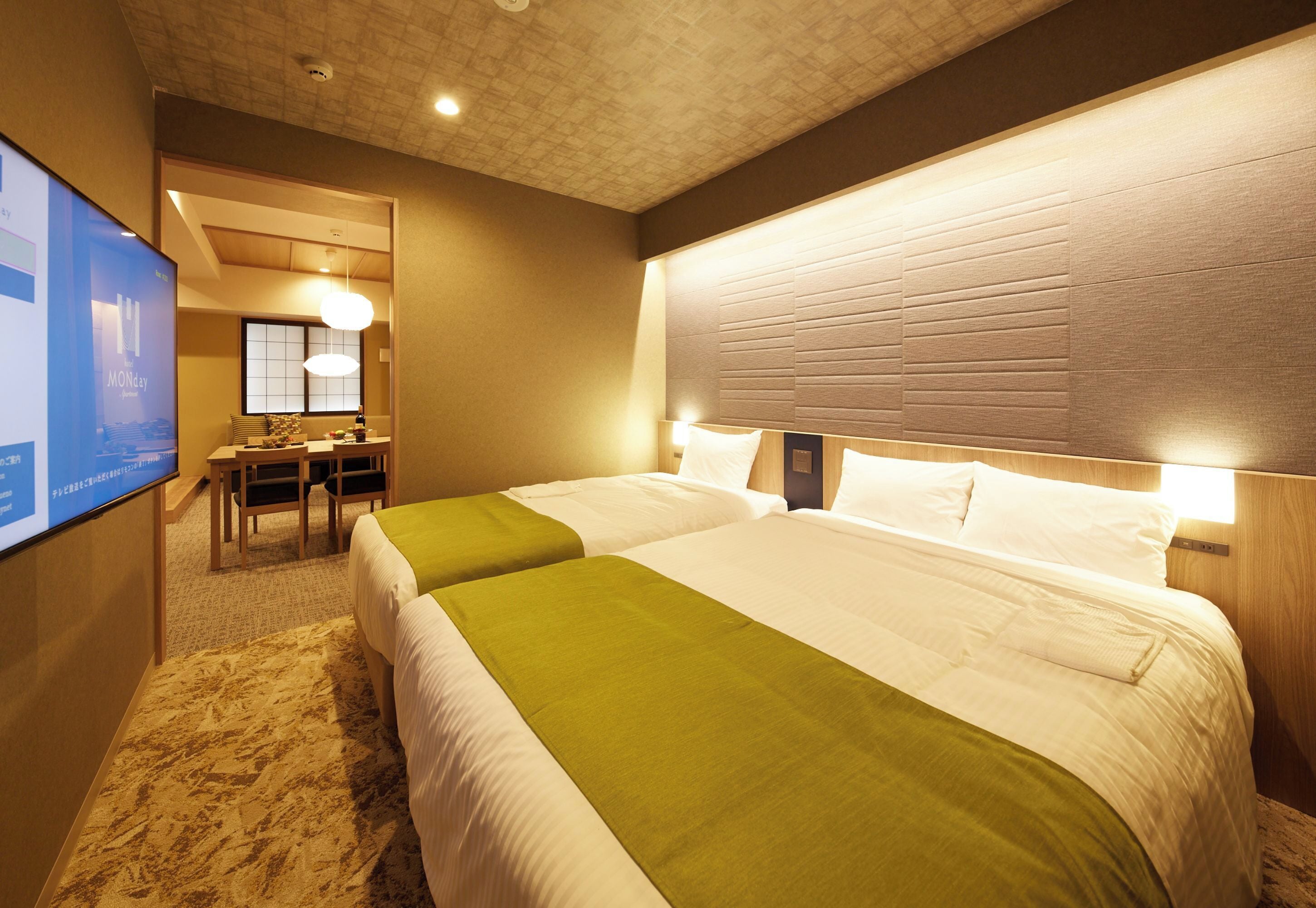 A hotel room with two beds, a desk, and a television.