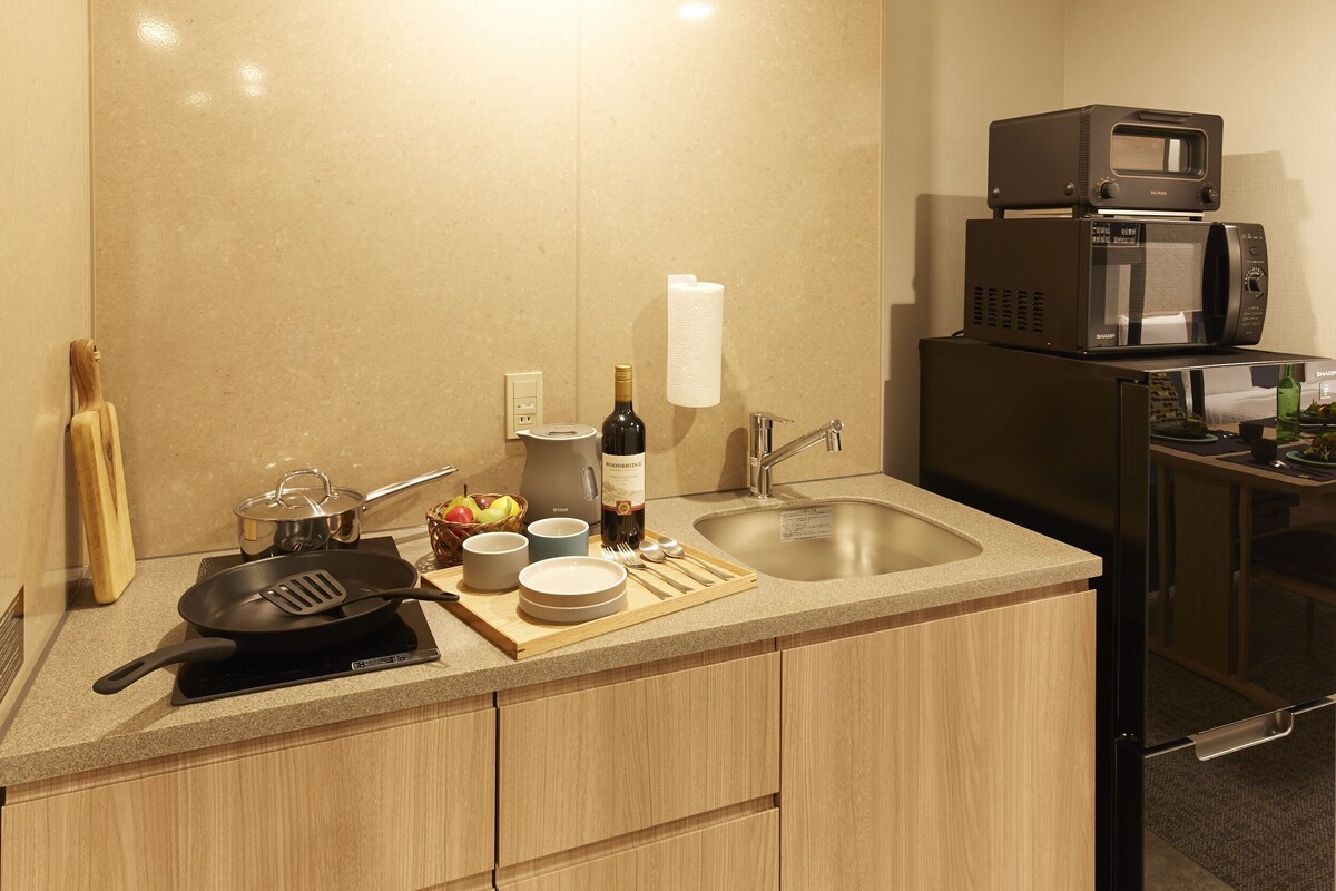 A kitchen with a microwave, toaster, sink, and various utensils.