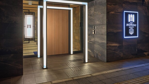 A hotel entrance with a modern design, featuring a wooden door and a neon sign indicating "hotel MONDAY." - MONday Apart Premium Ueno (Tokyo)