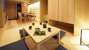 A modern kitchen with wooden cabinets, a dining table, and a TV. - MONday Apart Premium Ueno (Tokyo)