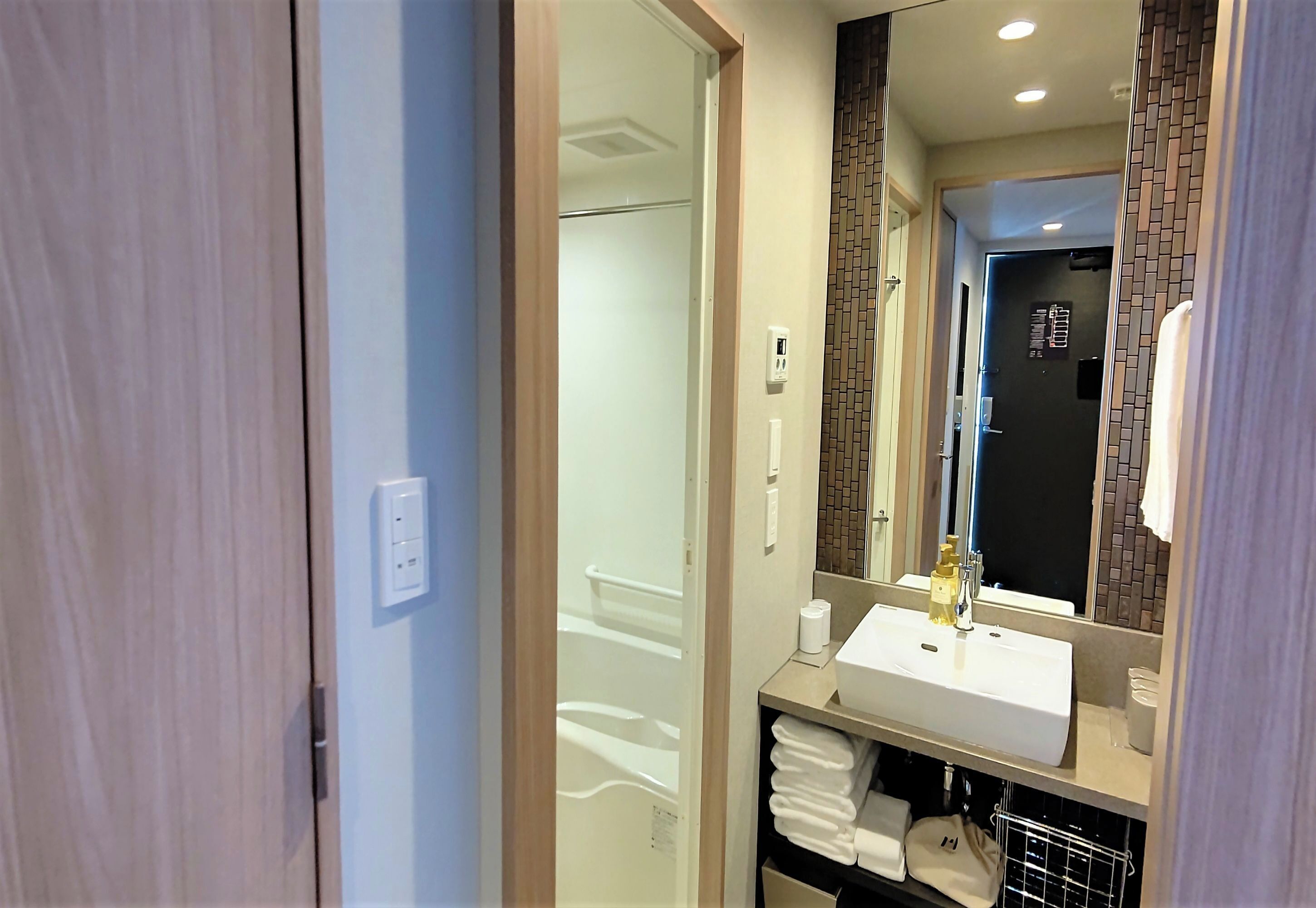 Un baño moderno con un lavamanos blanco, un espejo y un perchero para toallas.