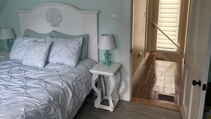 A bedroom with a bed, bedside tables, and a door leading to a hallway. - West Harwich- Cozy Cape House walking distance to Dennis Port & Bell's Neck path (Harwich)