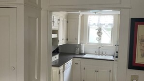 A kitchen with white cabinets, a black countertop, and a window with decorative elements. - West Harwich- Cozy Cape House walking distance to Dennis Port & Bell's Neck path (Harwich)