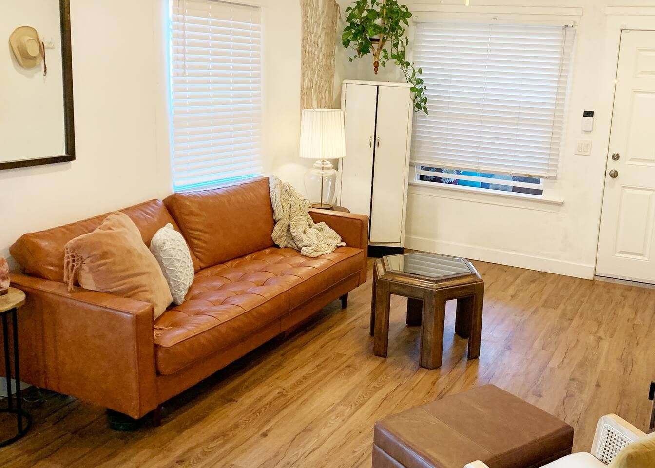 Un salon avec un canapé en cuir marron, une petite table basse en bois et un meuble blanc.