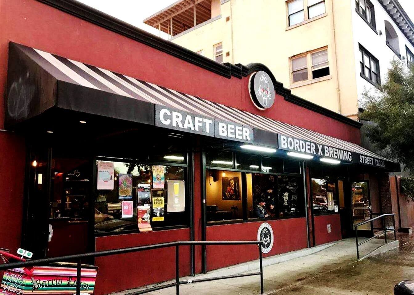 Ein rotes Gebäude mit einer schwarzen Markise und einem Schild, auf dem 'CRAFT BEER BORDER X BREWING STREET TACOS' steht.