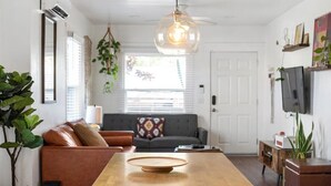 Un salon moderne avec une table basse en bois, un canapé gris et un luminaire suspendu.