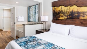 Une chambre d’hôtel avec un lit, un bureau, une chaise, une table de chevet, une lampe et un tableau au mur.