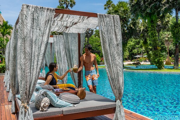 Una cabaña privada con toldo, piscina y exuberante vegetación de fondo.
