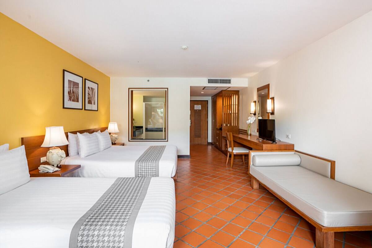 Ein Hotelzimmer mit zwei Betten, einem Schreibtisch, einem Stuhl und einem Fernseher.