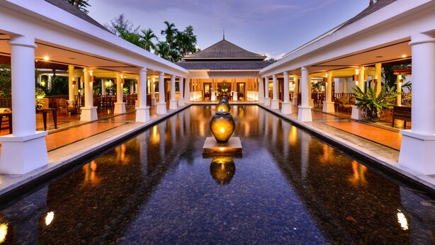 A hotel lobby with a central water feature, columns, and seating areas. - Naithonburi Beach Resort (Sa Khu)
