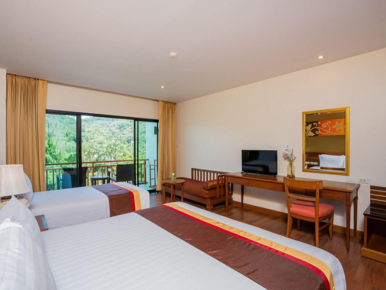 Habitación de hotel con dos camas, un escritorio, una silla, un televisor y un balcón con cortinas.