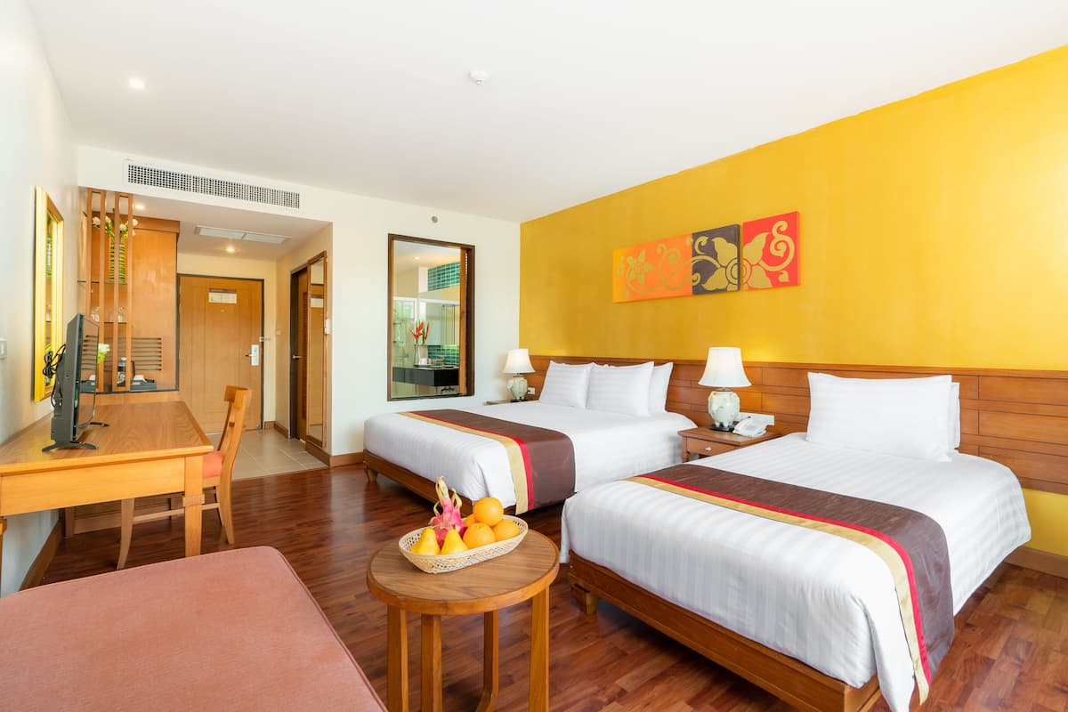 Ein Hotelzimmer mit zwei Betten, einem Schreibtisch und einem kleinen Tisch mit Obst.