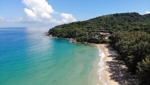 A coastal area with a beach, a forested hill, and a cluster of buildings. - Naithonburi Beach Resort (Sa Khu)