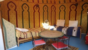 A room with two beds, a round table, and a fan. - Appartement Typique Casbah Tanger Lieu Historique (Tangier)