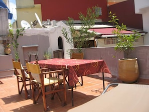 Un patio con mesa y sillas, plantas en macetas y una antena parabólica.