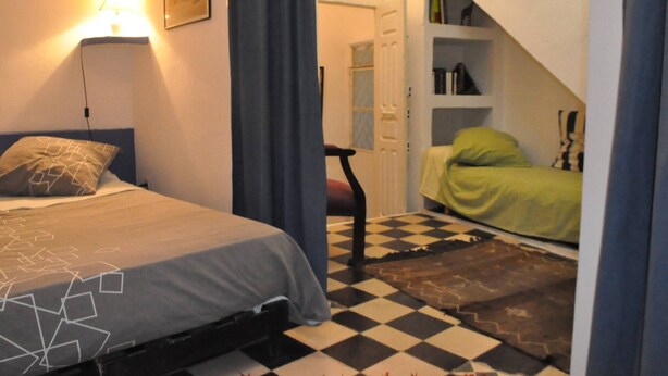 A bedroom with a bed, a chair, a bookshelf, and a staircase. - Appartement Typique Casbah Tanger Lieu Historique (Tangier)