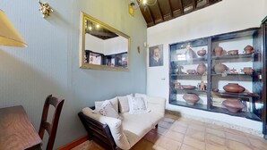 A living room with a sofa, chairs, a table, a mirror, and a display of pottery. - Tenerife Village Finca Paraiso (San Cristóbal de La Laguna)