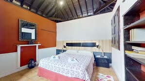 A bedroom with a bed, bedside tables, a mirror, and a bookshelf. - Tenerife Village Finca Paraiso (San Cristóbal de La Laguna)