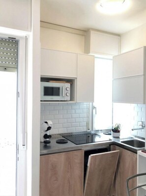 A modern kitchen with white cabinets, a microwave, a stove, and a sink.