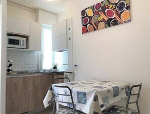 A kitchen with white cabinets, a microwave, and a dining table with a patterned tablecloth.