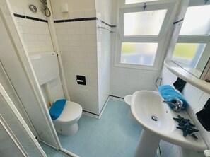 Une salle de bain équipée de toilettes, d’une douche, d’un lavabo et d’une fenêtre.