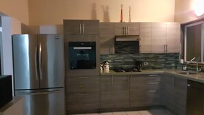 Eine moderne Küche mit Edelstahlgeräten, einer gefliesten Spritzschutzwand und Holzschränken.