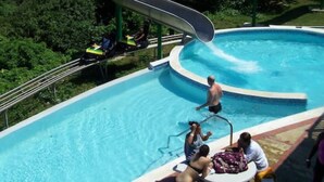 Une piscine avec un toboggan, entourée de verdure.