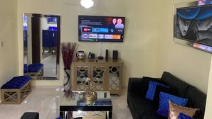 A living room with a TV, sofa, coffee table, and decorative items. - Entire Apartment Tu Nido De Amor 😍netflix Wifi (Santo Domingo)