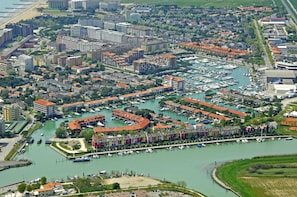 An aerial view of a marina with boats, surrounded by residential buildings and a beach. - Beautiful House in a Great Location Near the Beach by Beahost Rentals (Caorle)