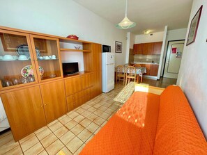 A compact living space with a kitchenette, a dining area, and a sofa.