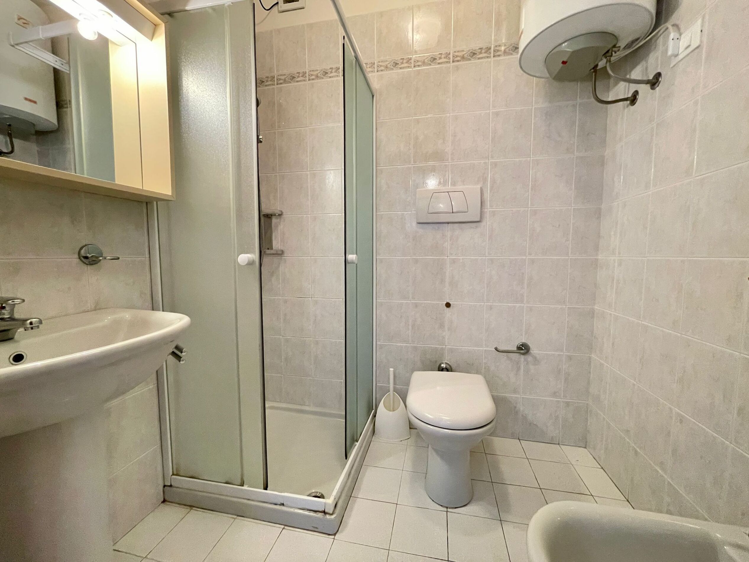 Een badkamer met een douchecabine, een wastafel, een toilet en een bad.
